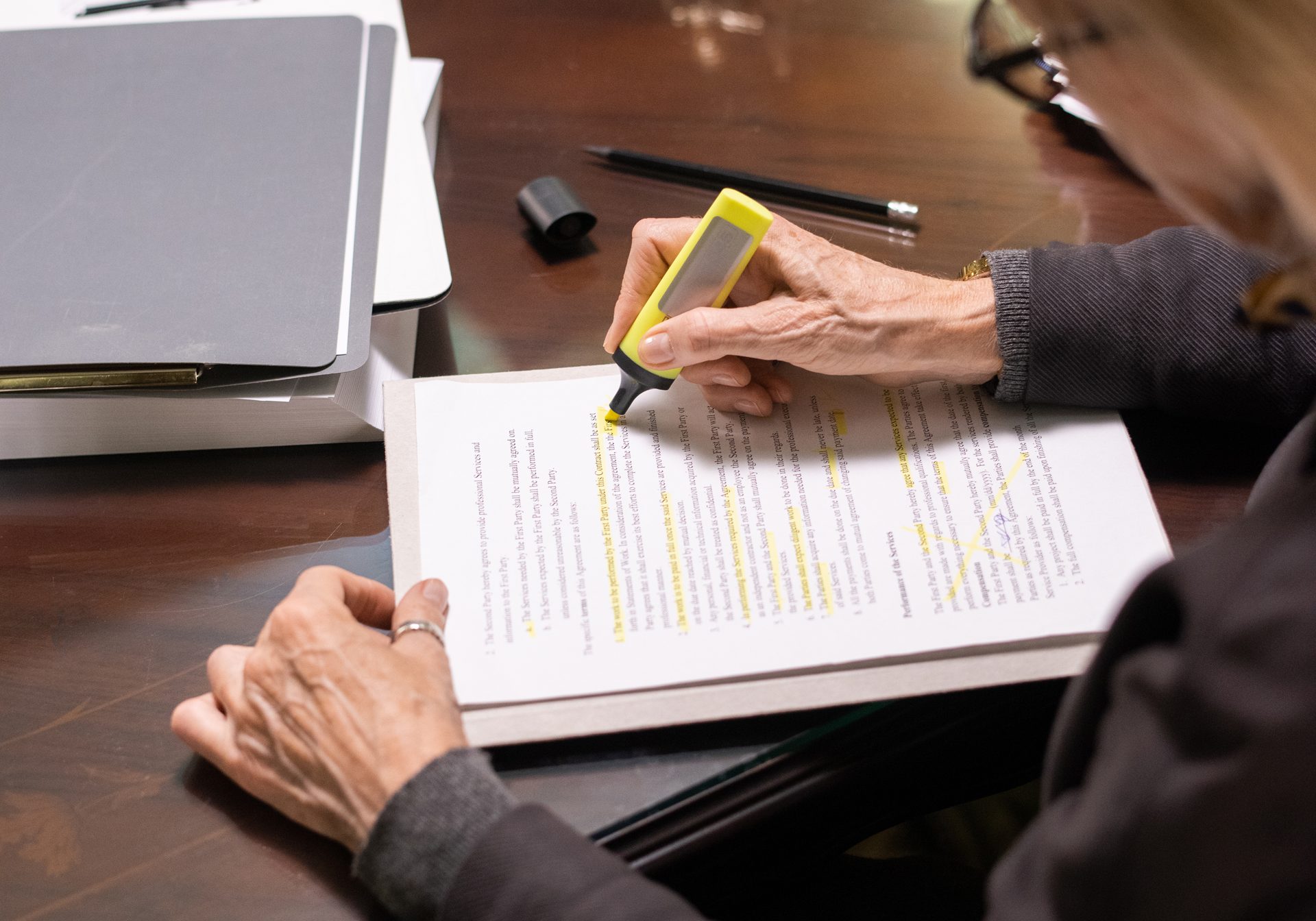 Contemporary mature businesswoman or lawyer highlighting terms and conditions of new contract by workplace